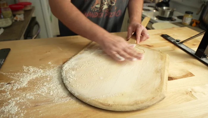 Lightly flour the wooden peel to remove any residue.
