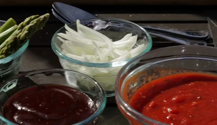 Build your pizza with your desired toppings. The video suggests tomato sauce, green and red peppers, and mozzarella cheese.