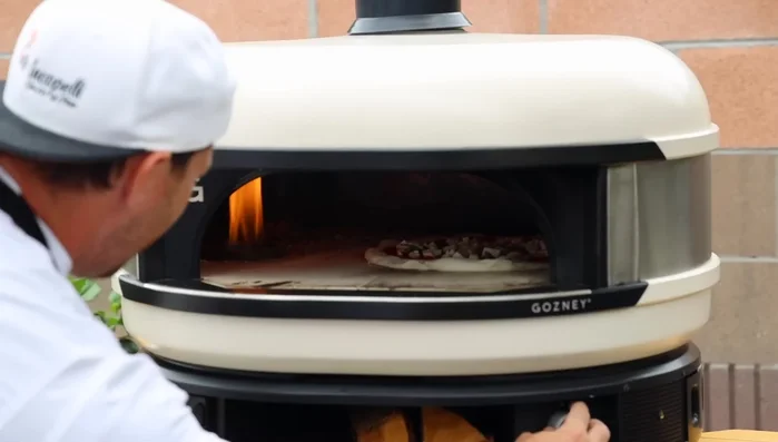 Monitor the pizza's bottom. If it's cooking too fast, use the peel to lift and reposition the pizza away from the direct heat. If the top isn't cooking fast enough, move the pizza closer to the heat source.