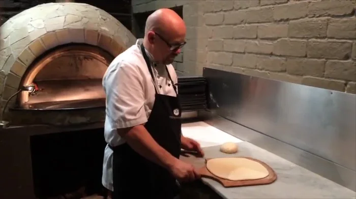 Gently roll out and dock the pizza base to prevent bubbling.