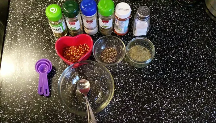 Gather ingredients: oregano, basil, garlic powder, thyme, fennel, paprika powder, black pepper, red chili, and salt.