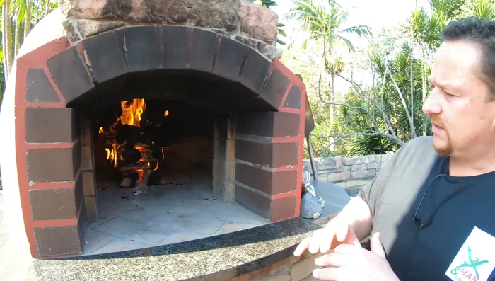 Add more wood to build a larger fire in the center, ensuring the oven floor is thoroughly heated.