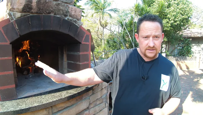 Add more wood to build a larger fire in the center, ensuring the oven floor is thoroughly heated.