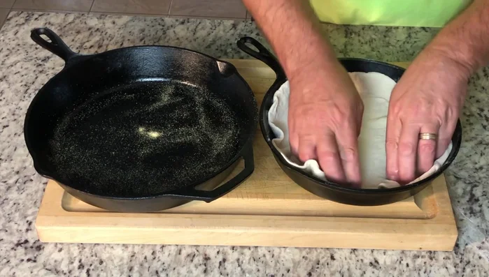 Place pizza dough into hot pans. Press edges to create a crust.