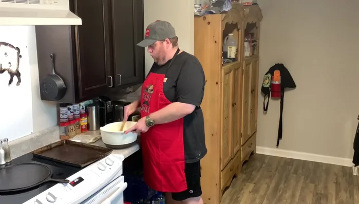Man mixing sticky pizza dough in bowl
