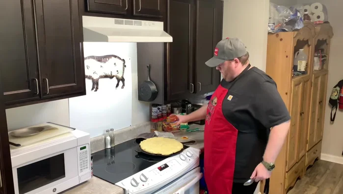 Man adding toppings to pizza crust