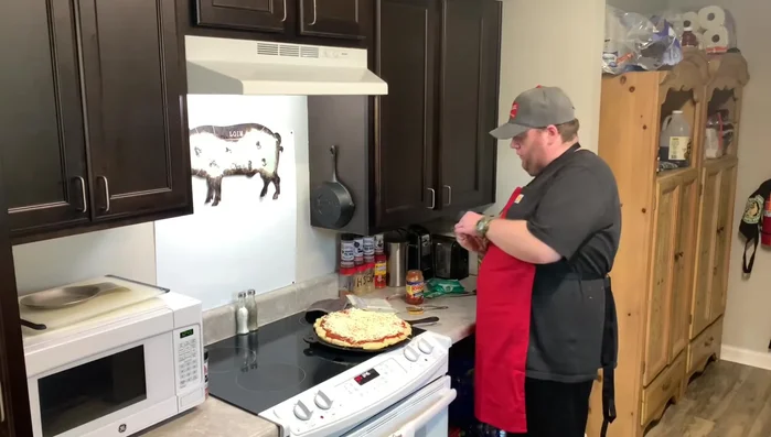 Man adding toppings to a pizza