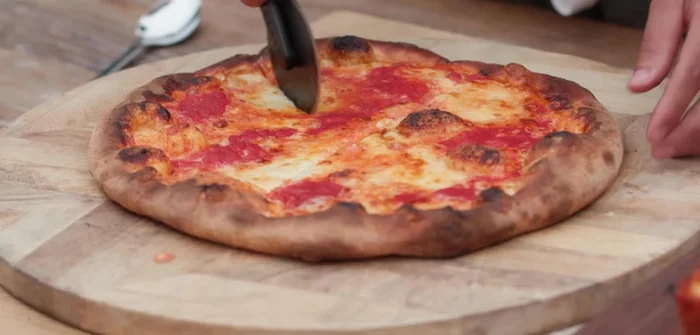 Add cheese, then bake at a lower temperature and slower than Neapolitan, rotating as needed until crust is golden brown and cheese is caramelized.