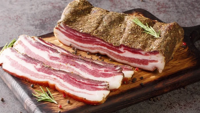 Sliced pancetta on wooden board