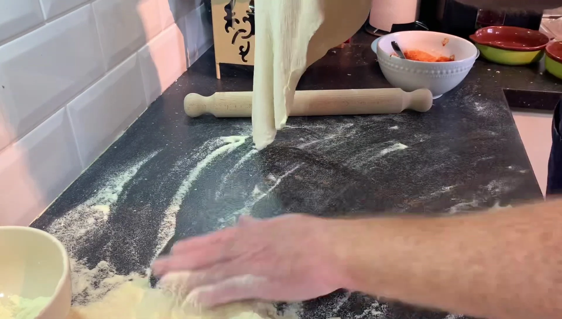 Rolling pizza dough with a rolling pin.