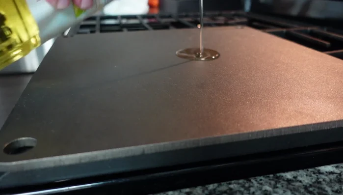 Apply a thin layer of canola oil to the pizza steel, covering the entire surface.