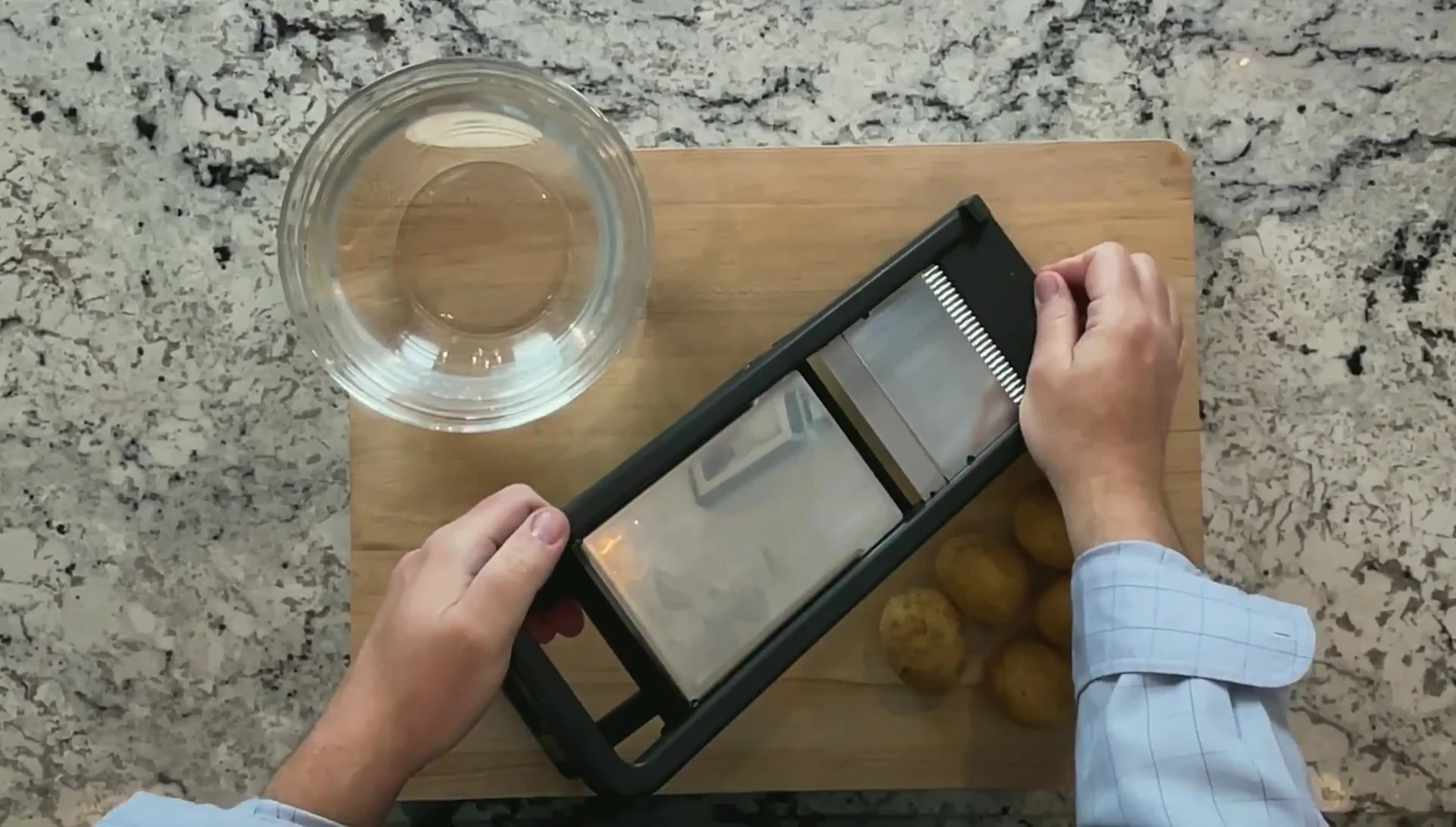 Close-up of mandoline slicer being used to slice potatoes.