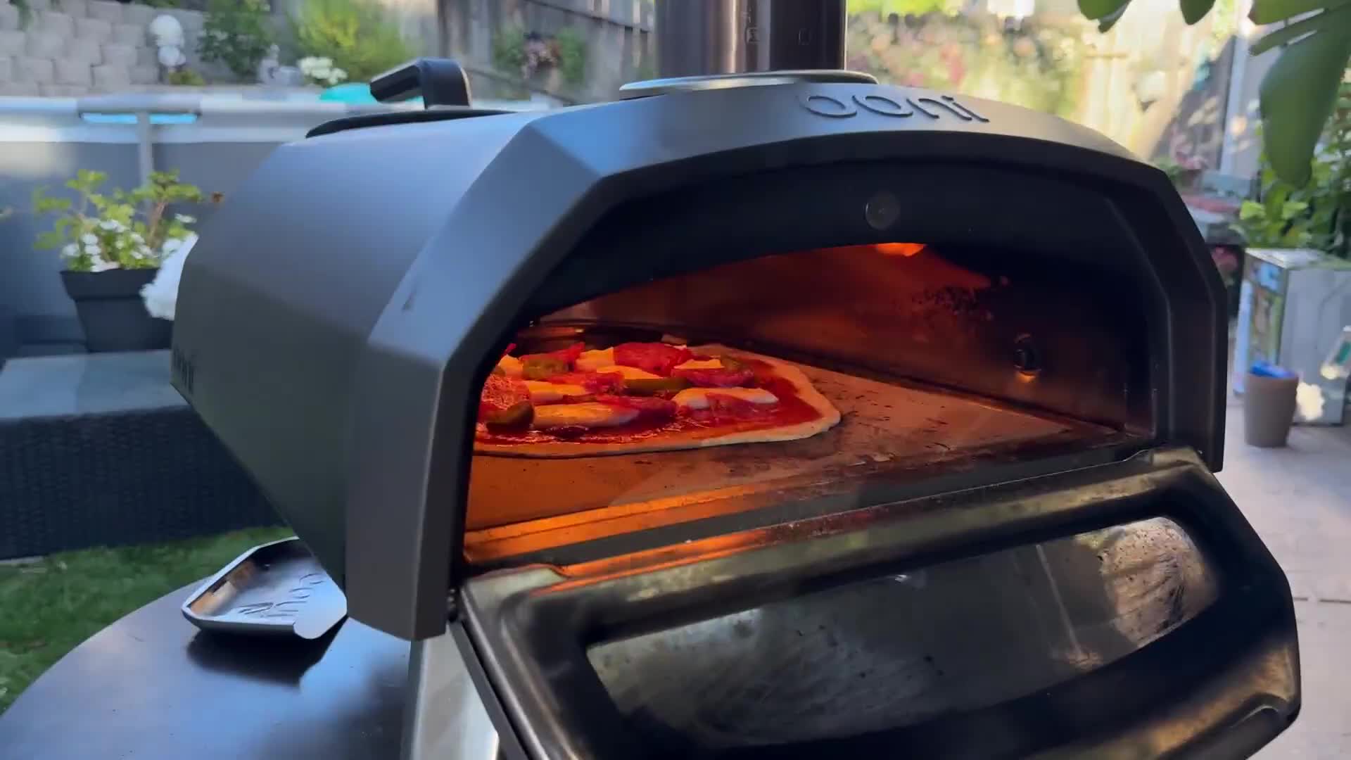 The pizza being carefully placed into the hot oven.