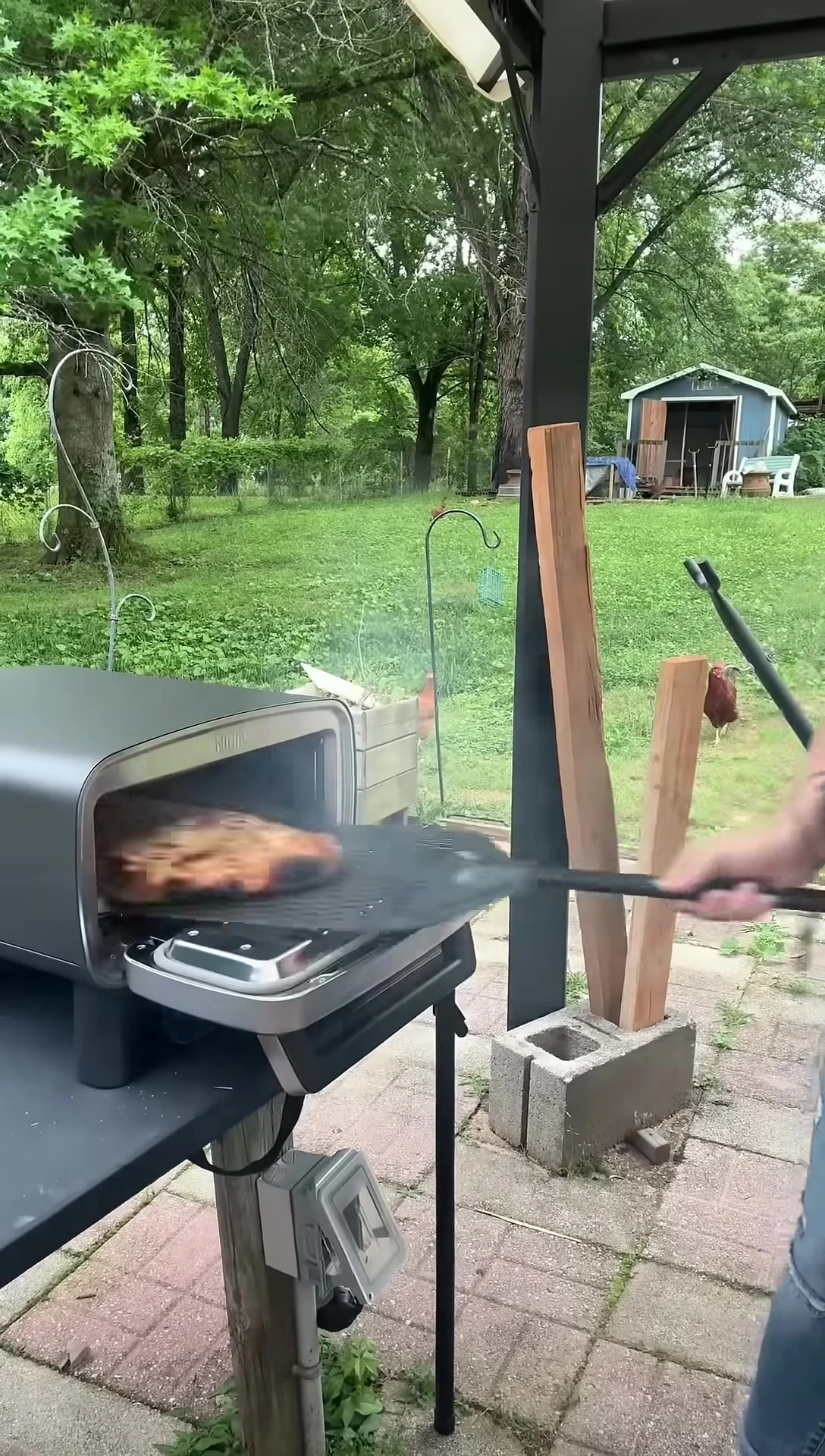 The first pizza being taken out of the oven.