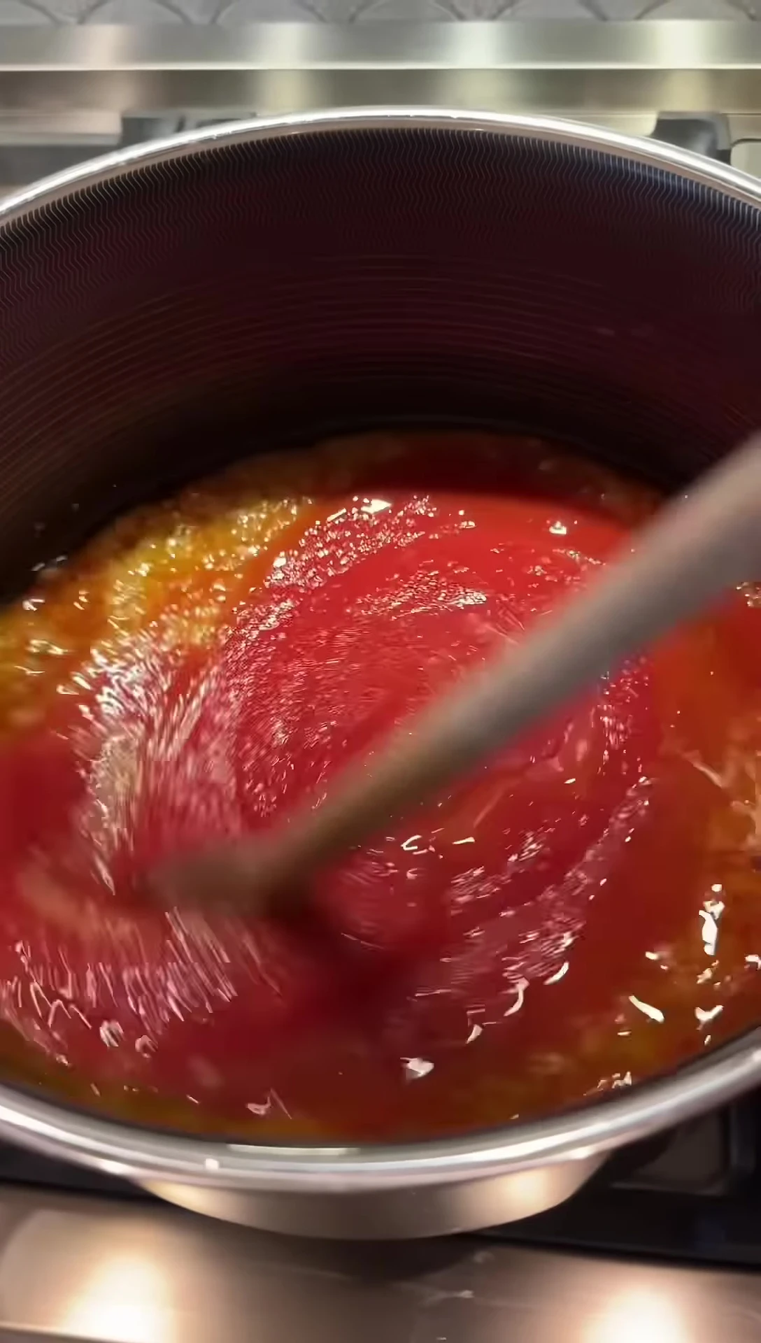 Stirring the sauce in the pan after adding tomatoes.